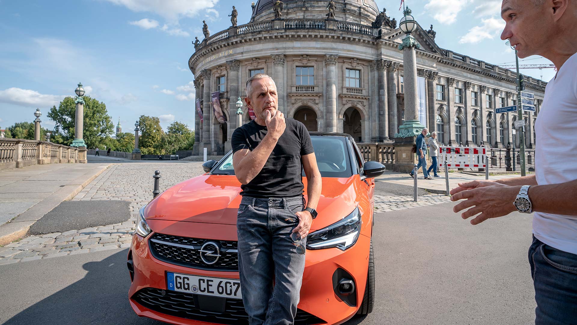 Schauspieler Tim Wilde lehnt in Berlin an einem Opel Corsa-e.